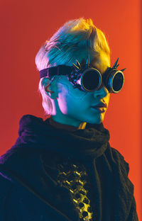 Young woman wearing sunglasses against yellow background