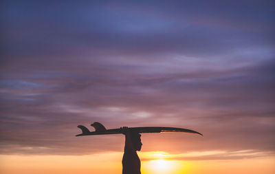 Close-up of man carrying surfboard on head while standing at beach