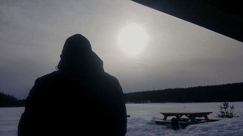 Rear view of silhouette man on snow against sky during sunset