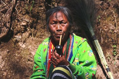 Portrait of woman smoking pipe while sitting outdoors