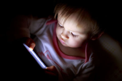 Close-up of child using digital tablet in darkroom