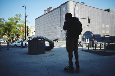 Man standing on footpath in city