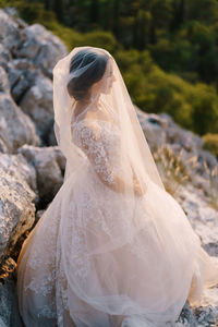 Side view of woman wearing gown standing on rock