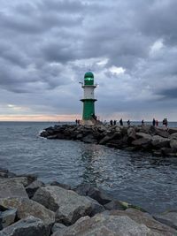 Lighthouse by sea against sky