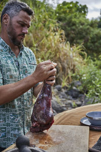 Chef preparing local venison leg for roasting on barbecue