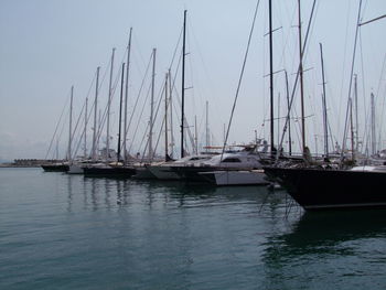 Sailboats moored on sea against sky