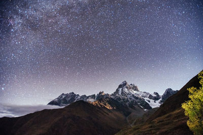 Scenic view of snowcapped mountains against sky at night