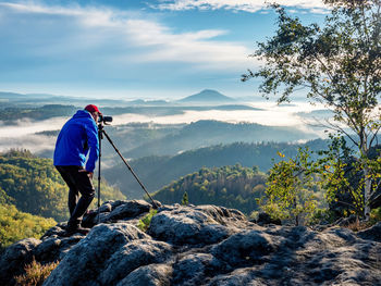 Outdoor travel photographer journalist holding a dslr camera in mountain background. man takes photo