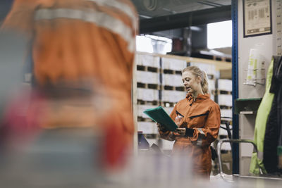 Female blue-collar worker discussing over file with male coworker in warehouse