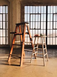 Ladder and stool against window in room