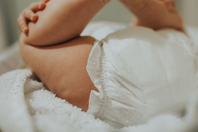 Low section of baby sleeping with feet up on bed