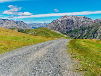 Road leading towards mountains against sky