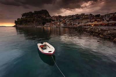 Boat moored on sea against sky during sunset