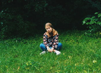 Full length of girl sitting cross legged on grassy field