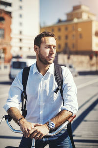 Thoughtful businessman with bicycle standing on city street