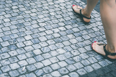 Low section of woman standing on cobblestone