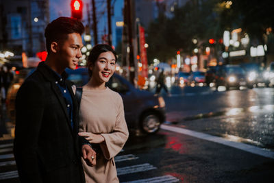 Young couple standing on street in city at night