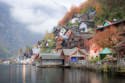 Houses by lake and buildings against sky