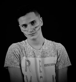 Portrait of young man standing against black background