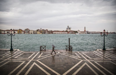 Person walking by grand canal in city