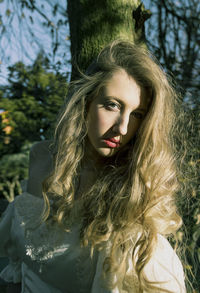 Portrait of beautiful young woman against trees