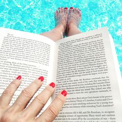 Low section of person in pool with book