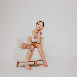 Portrait of young woman sitting against white background