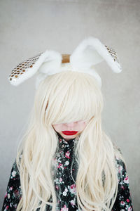 Close-up of woman wearing rabbit ears headband against wall