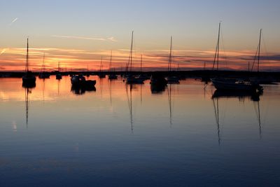 Boats moored in sea at sunset