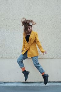 Hipster woman jumping against wall