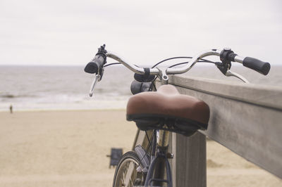 Close-up of bicycle on beach against sky