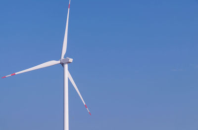 Low angle view of windmill against blue sky