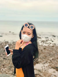 Young woman holding mobile phone at beach