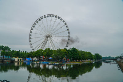 Ferris wheel by lake against sky