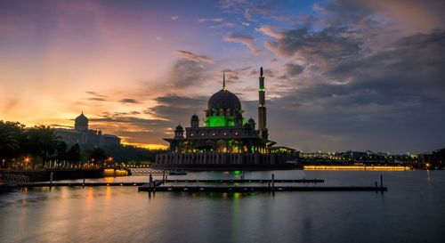 Putra mosque by lake against sky during sunset in city