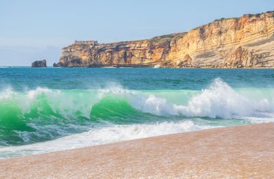 Wave and cliffs in atlantic ocean on the beach in nazaré, portugal.