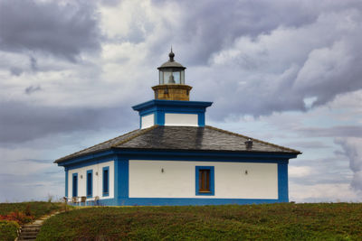 Building on field against cloudy sky