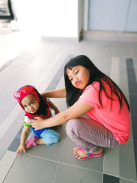 High angle view of cute sisters on tiled floor