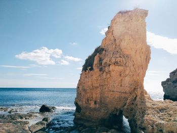 Rock formation by sea against sky