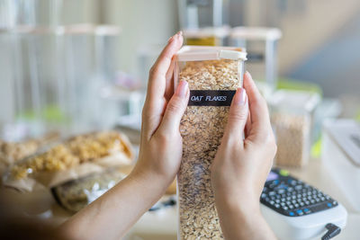 Cropped hand of woman holding oat flakes in container