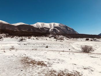 Scenic view of snowcapped mountains against clear blue sky