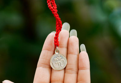 Close-up of cropped hand holding om symbol necklace