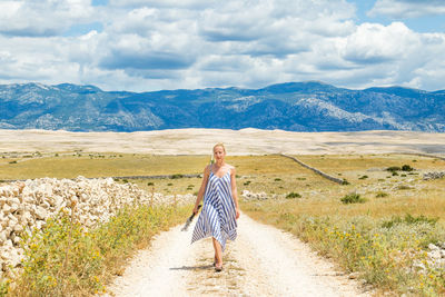 Woman with arms raised on mountain against sky