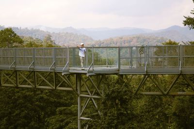 Man standing by railing against sky