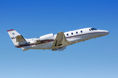 Low angle view of airplane flying against clear blue sky