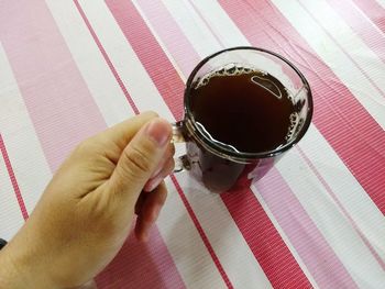 Close-up of hand holding coffee cup on table