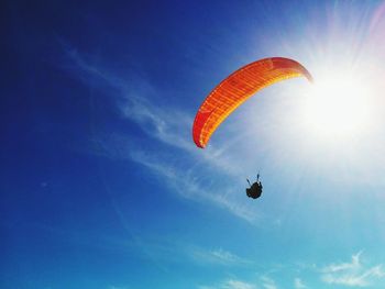 Low angle view of person paragliding against blue sky