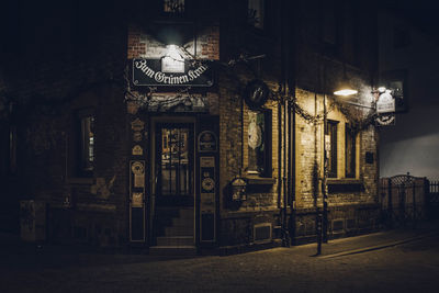 Illuminated street light by building at night