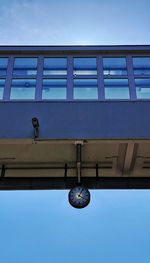 Low angle view of clock hanging on street against sky