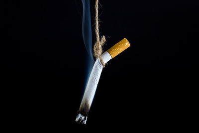 Close-up of cigarette smoking against black background